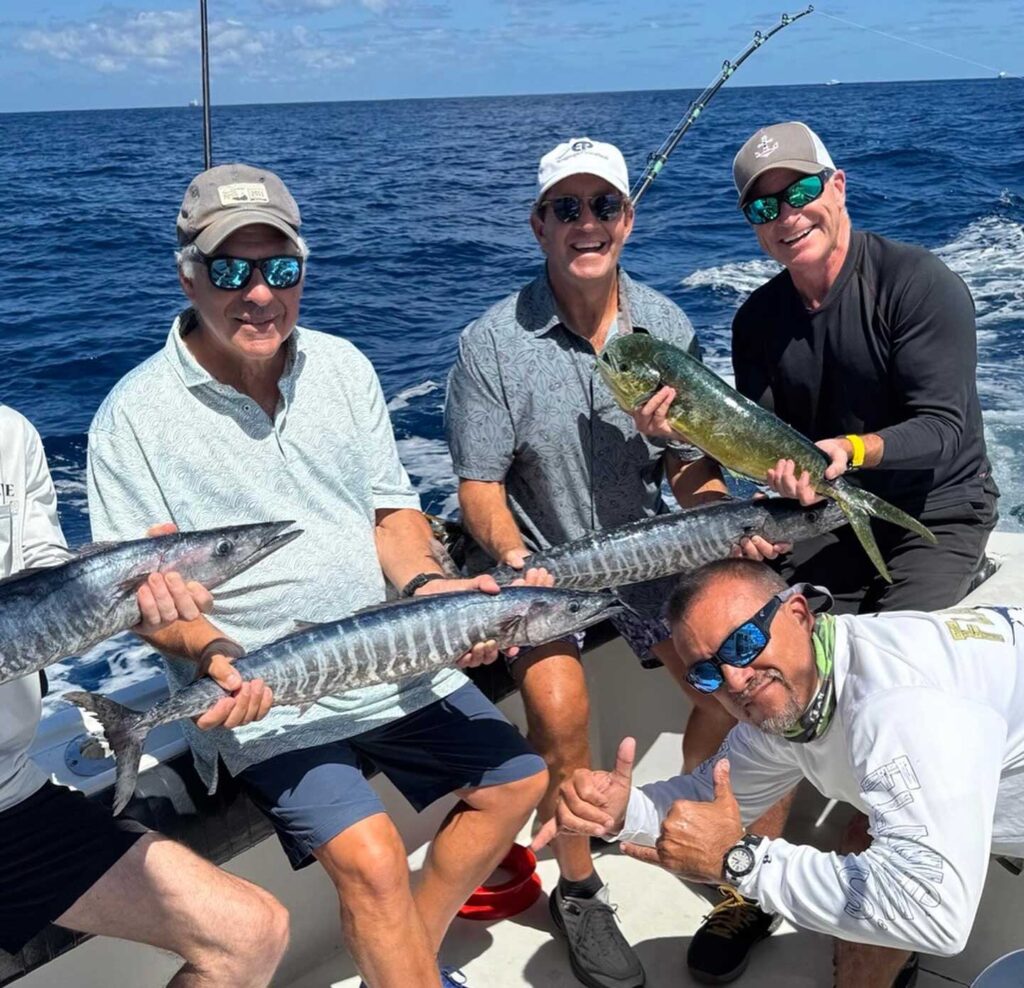 A group of happy anglers with three wahoo and a mahi